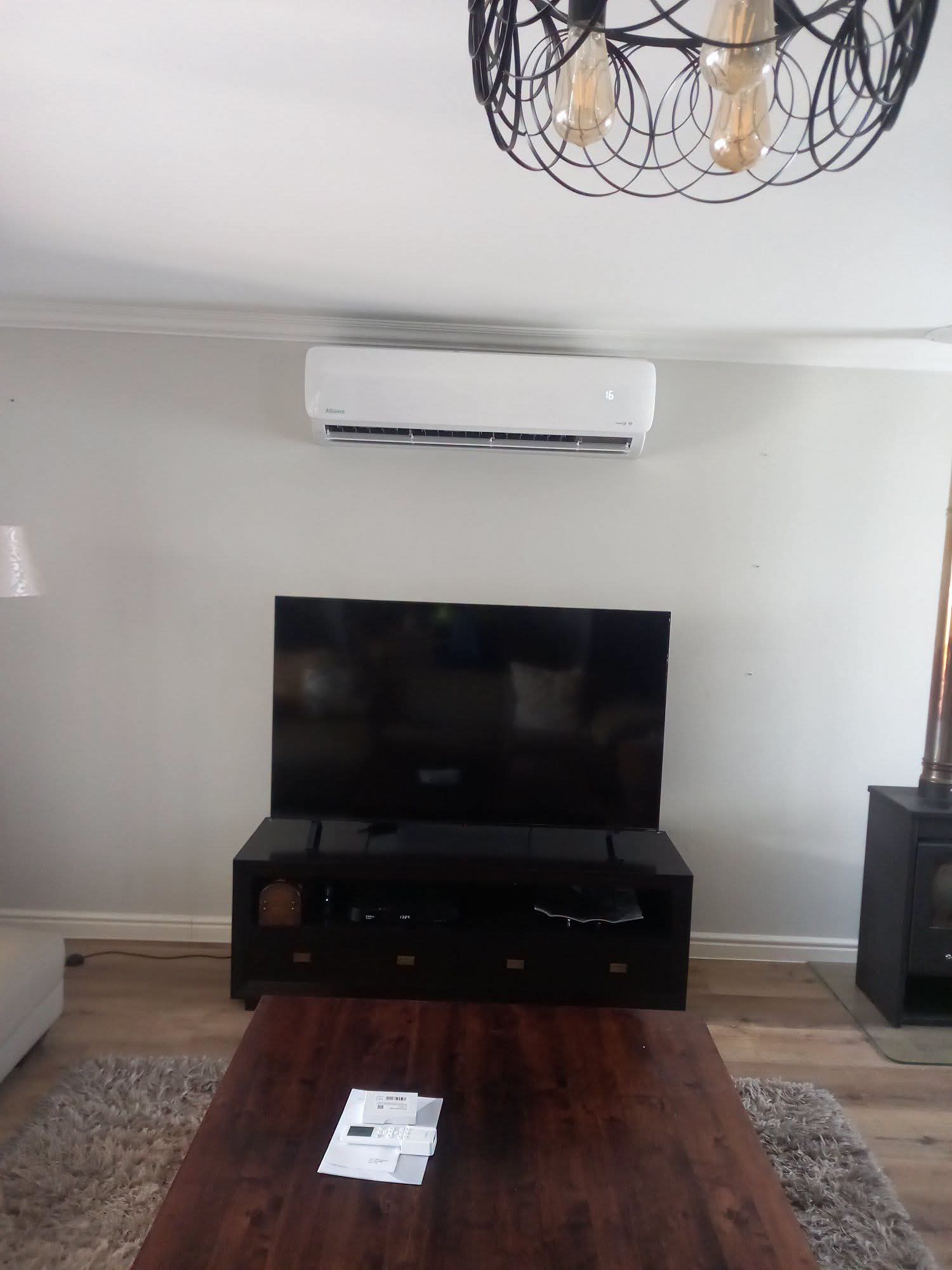 Split-unit air conditioner installed above a TV unit in a residential living room